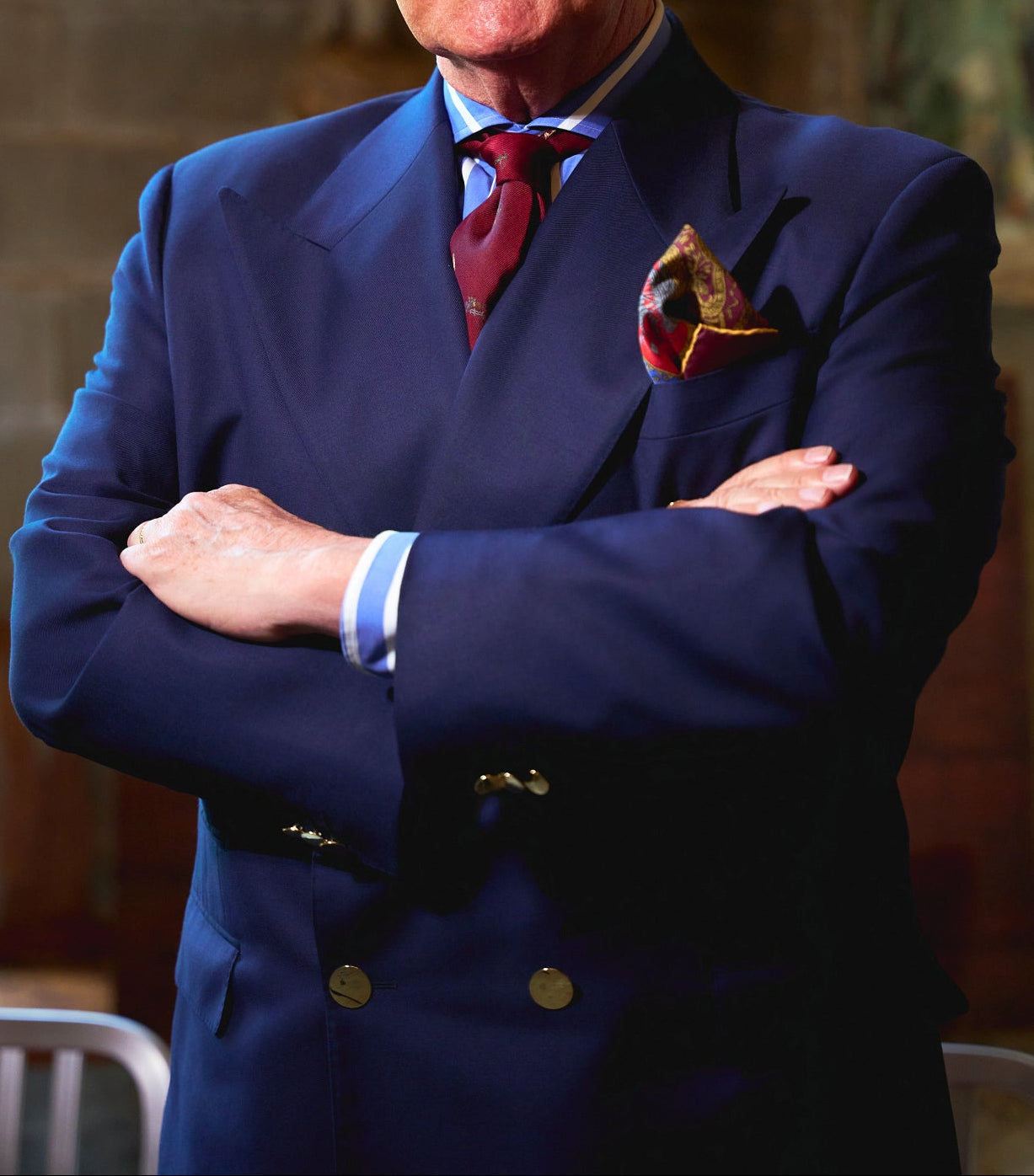 Man in a blue suit with a red tie standing in a room with artwork on the wall.