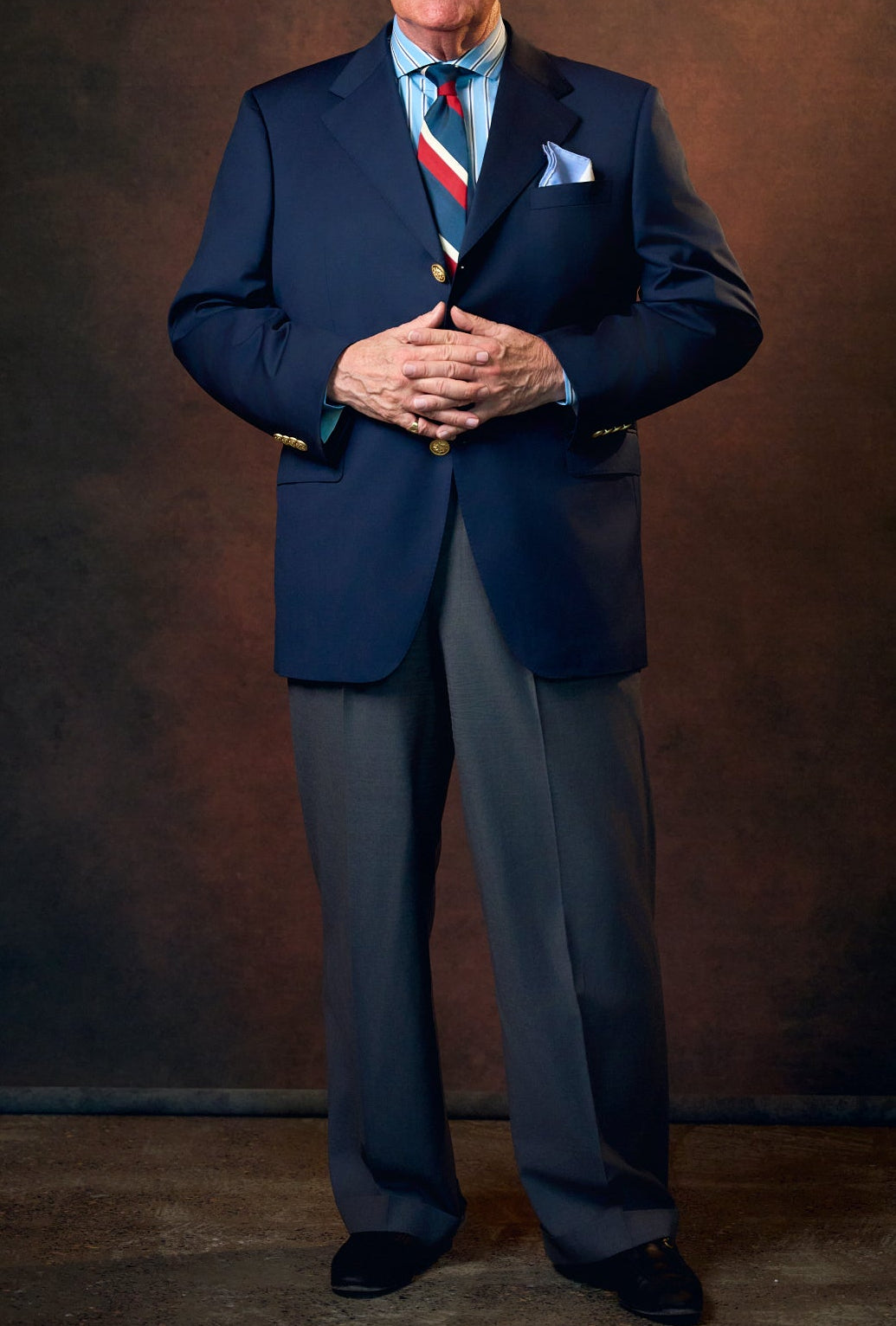 Man in a suit standing against a brown background